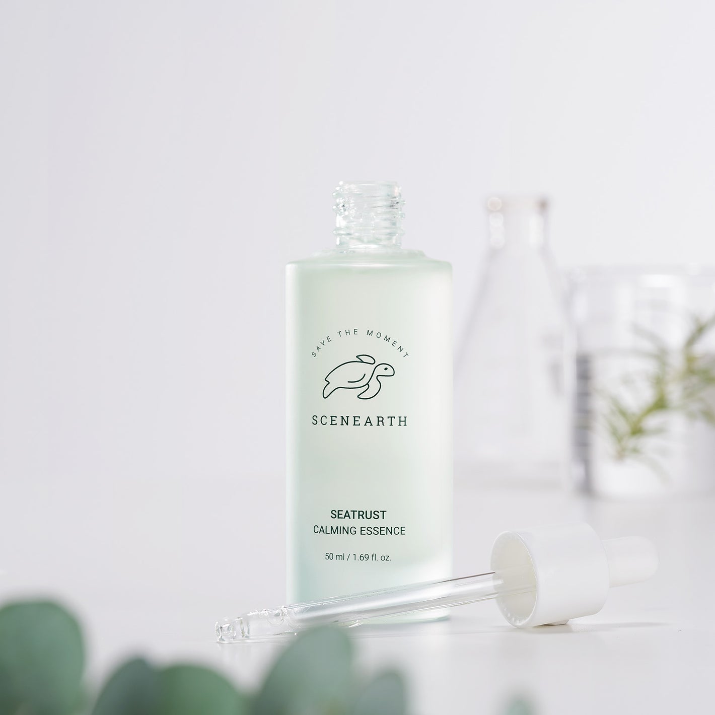 Scenearth Seatrust Calming Essence product in front of a blurry background of beakers full of water and botanicals